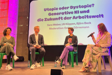 Vier Personen sitzen auf der Bühne und führen eine Diskussion